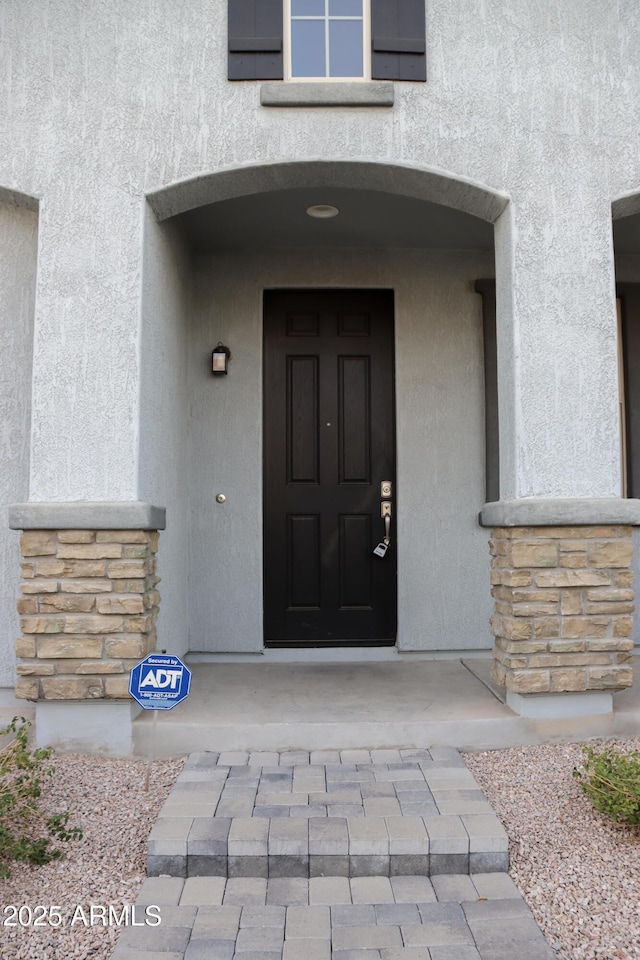 doorway to property with stone siding and stucco siding