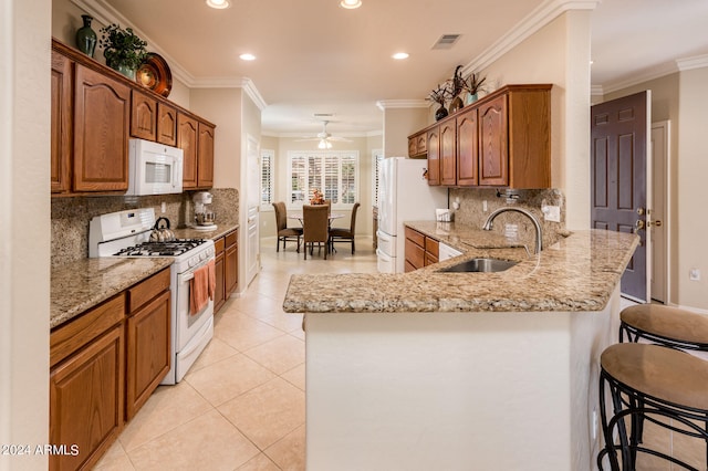 kitchen featuring sink, ceiling fan, a kitchen bar, white appliances, and tasteful backsplash