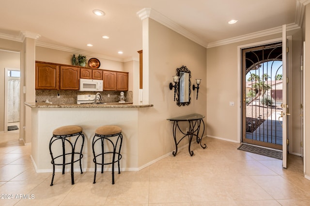 kitchen with a wealth of natural light, light tile flooring, tasteful backsplash, and light stone countertops