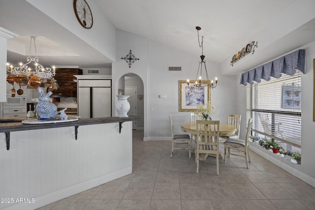 kitchen featuring light tile patterned floors, an inviting chandelier, built in appliances, a kitchen bar, and decorative light fixtures