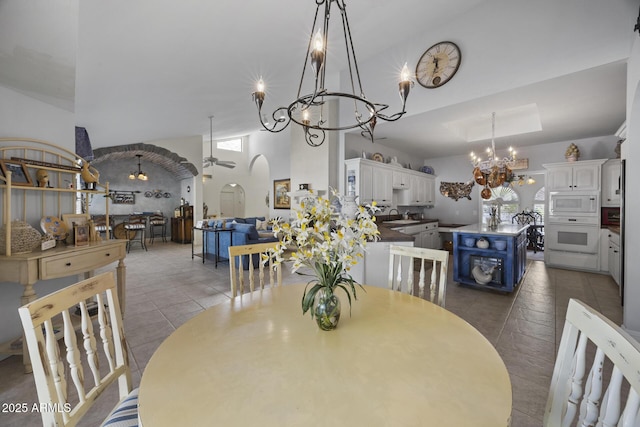 tiled dining area with a high ceiling, plenty of natural light, sink, and ceiling fan with notable chandelier