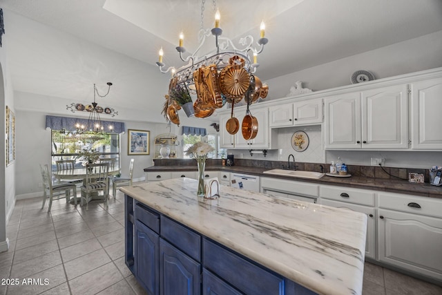 kitchen with blue cabinetry, white cabinetry, sink, and a notable chandelier