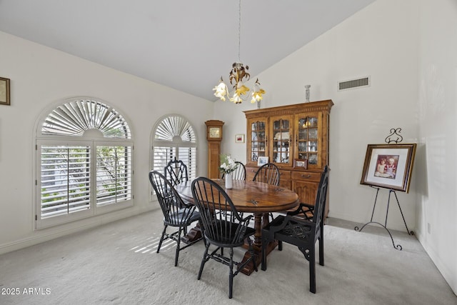 dining room featuring light carpet, high vaulted ceiling, and a chandelier