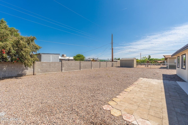 view of yard with a fenced backyard, an outbuilding, and a shed