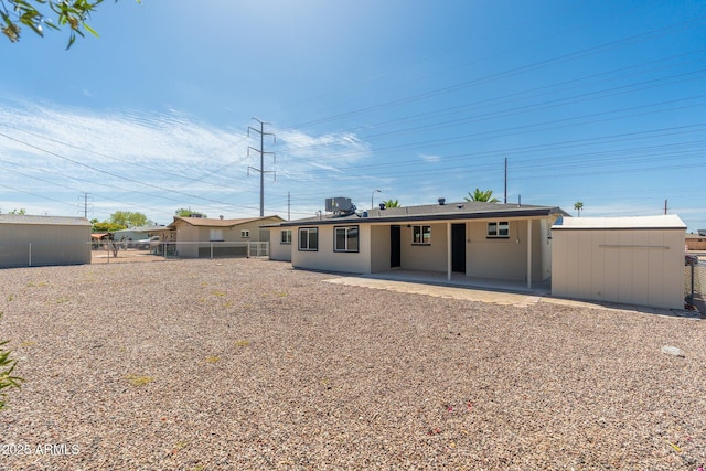 back of property featuring a storage shed, an outbuilding, central AC, fence, and a patio area