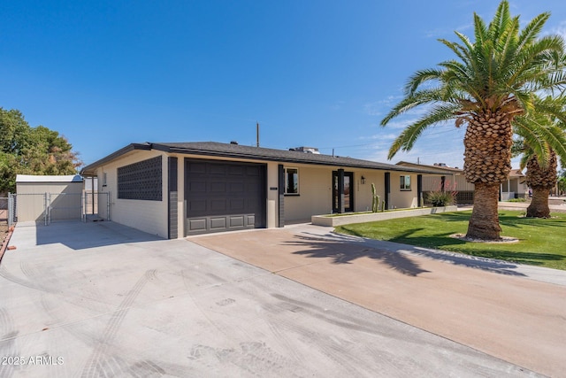 ranch-style house featuring a front lawn, a gate, driveway, fence, and an attached garage