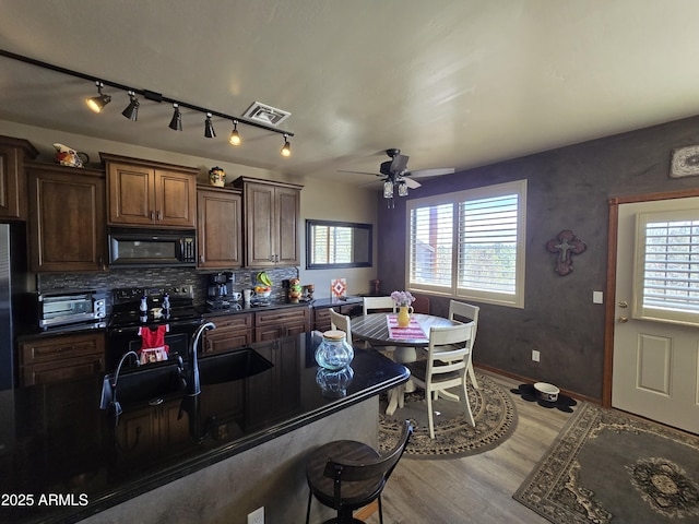 kitchen featuring backsplash, wood-type flooring, black appliances, and ceiling fan