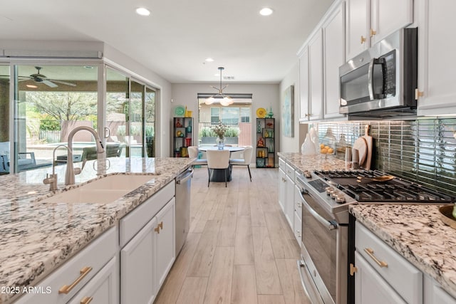 13186 W Via Dona Rd, Peoria, AZ 85383 - kitchen with stainless steel appliances, a sink, light wood-type flooring, white cabinets, and backsplash
