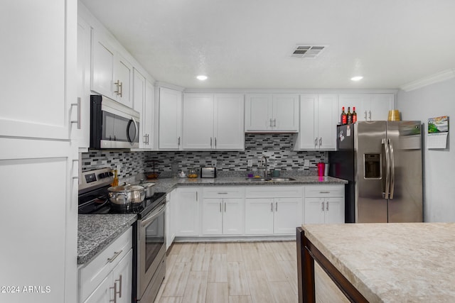 kitchen featuring stainless steel appliances, sink, decorative backsplash, and white cabinetry