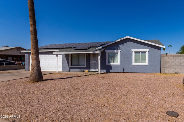 single story home with solar panels and a garage