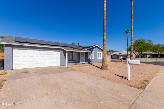 ranch-style home featuring a garage and solar panels