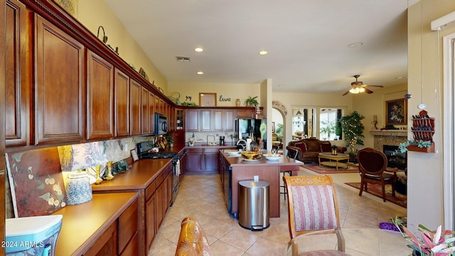 kitchen featuring light tile patterned flooring, sink, a center island, ceiling fan, and black appliances