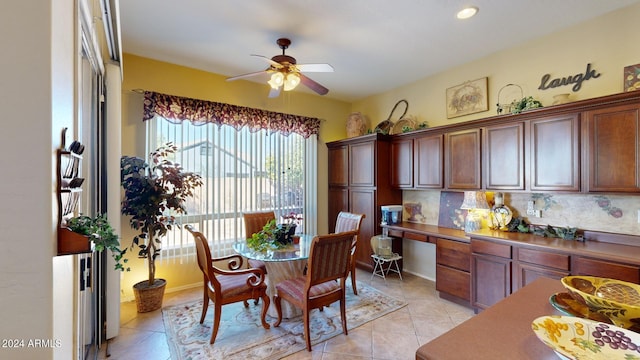 tiled dining space featuring built in desk and ceiling fan