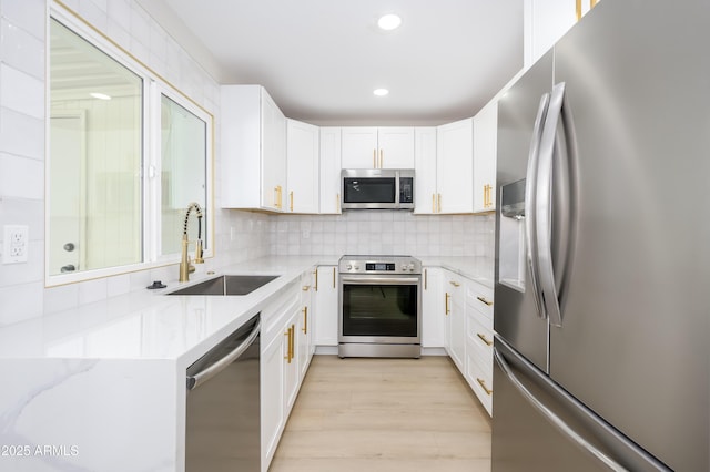 8341 E Keim Dr, Scottsdale, AZ 85250 - kitchen with appliances with stainless steel finishes, white cabinetry, tasteful backsplash, light stone countertops, and light wood-style flooring