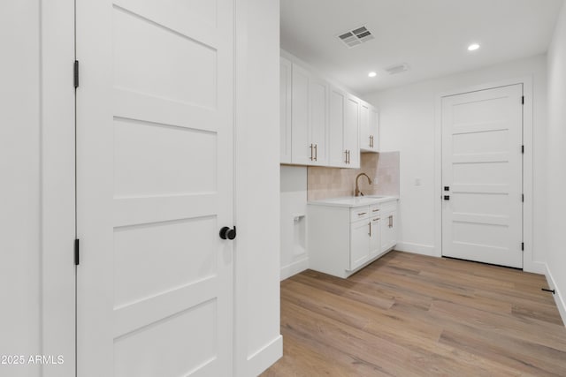 kitchen featuring backsplash, sink, white cabinets, and light hardwood / wood-style floors