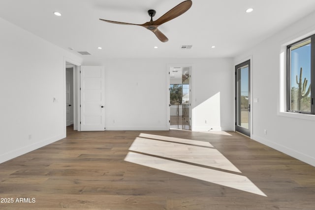 spare room with plenty of natural light, ceiling fan, and dark wood-type flooring