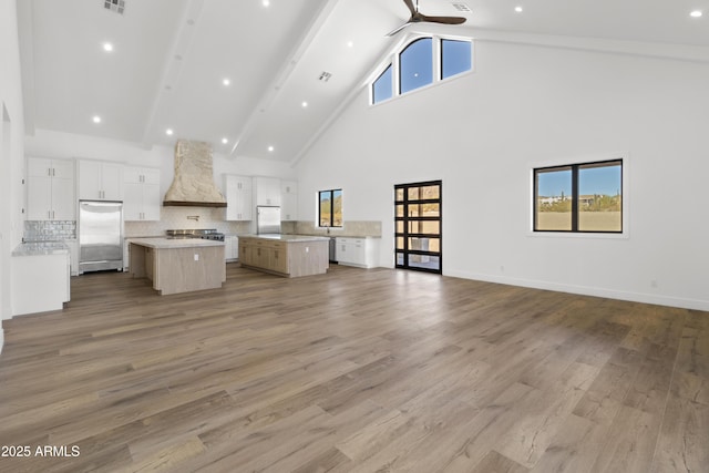 unfurnished living room featuring ceiling fan, beam ceiling, light hardwood / wood-style floors, and high vaulted ceiling