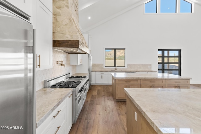 kitchen featuring white cabinetry, tasteful backsplash, light stone counters, high vaulted ceiling, and high quality appliances