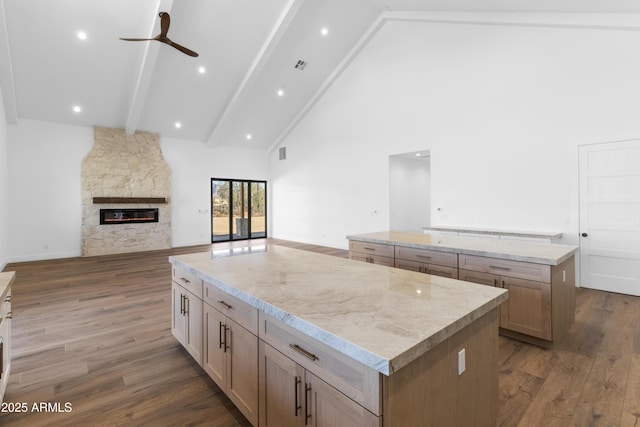 kitchen featuring a fireplace, wood-type flooring, ceiling fan, and a spacious island