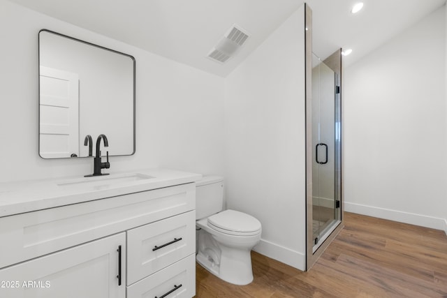 bathroom featuring hardwood / wood-style flooring, vanity, toilet, and a shower with shower door