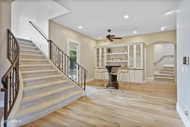 staircase with hardwood / wood-style flooring and ceiling fan