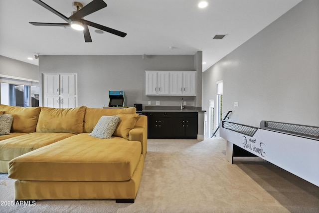 carpeted living room with ceiling fan and sink