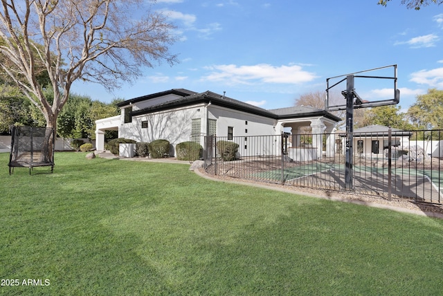 rear view of house with a fenced in pool, basketball hoop, and a lawn