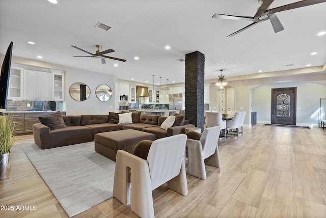 living room featuring light wood-type flooring, decorative columns, and ceiling fan