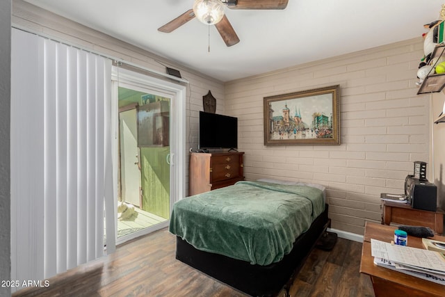 bedroom featuring baseboards, brick wall, a ceiling fan, and dark wood-style flooring