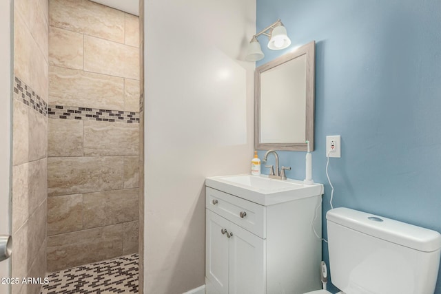 full bath featuring tiled shower, vanity, and toilet