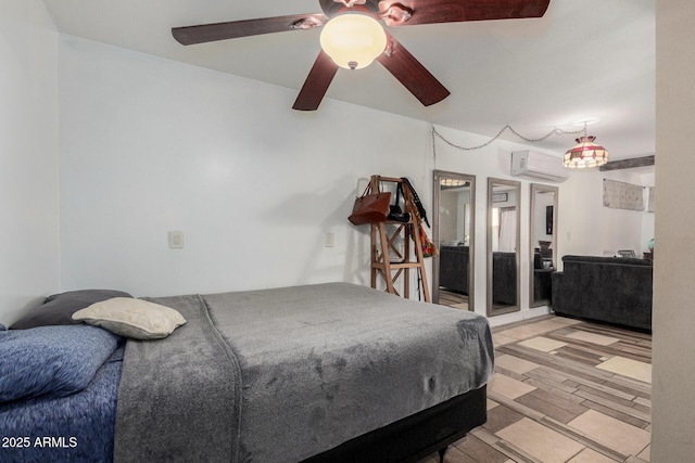 bedroom with a wall unit AC, light wood-style flooring, and a ceiling fan