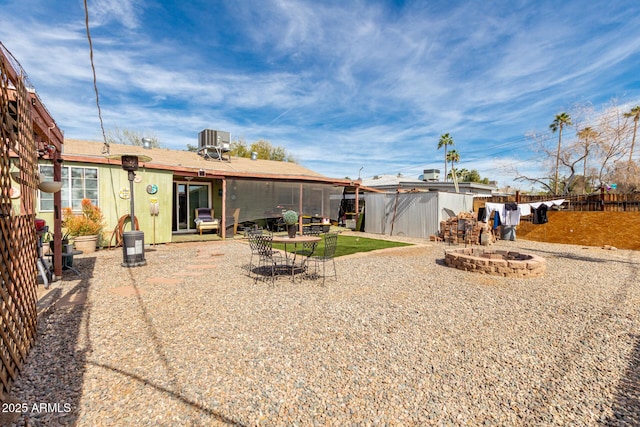 rear view of house featuring a patio area, central AC, fence, and a fire pit