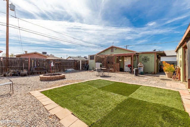 rear view of house featuring a patio area, an outdoor fire pit, a lawn, and a fenced backyard