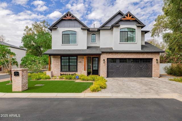 craftsman-style house featuring stucco siding, decorative driveway, a front yard, brick siding, and a garage