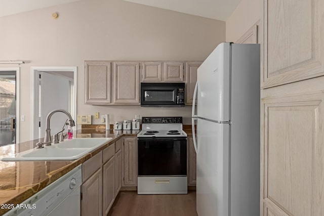 kitchen featuring white appliances, wood finished floors, a peninsula, vaulted ceiling, and a sink