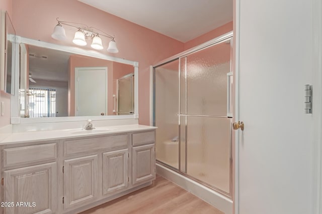 full bathroom featuring an enclosed shower, wood finished floors, and vanity