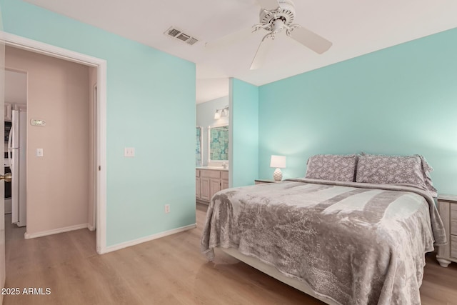 bedroom featuring baseboards, freestanding refrigerator, visible vents, and light wood-style floors