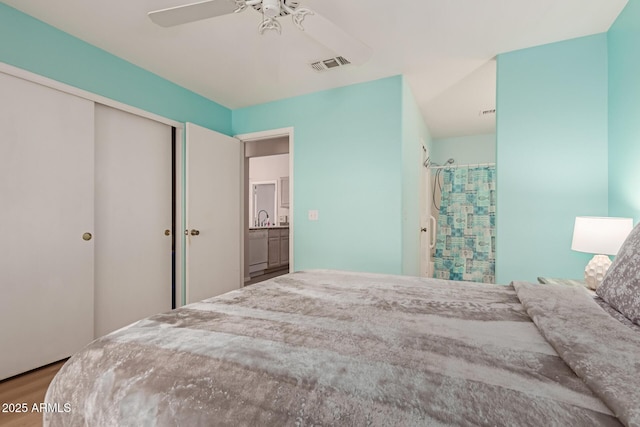 bedroom with a closet, visible vents, a ceiling fan, wood finished floors, and a sink