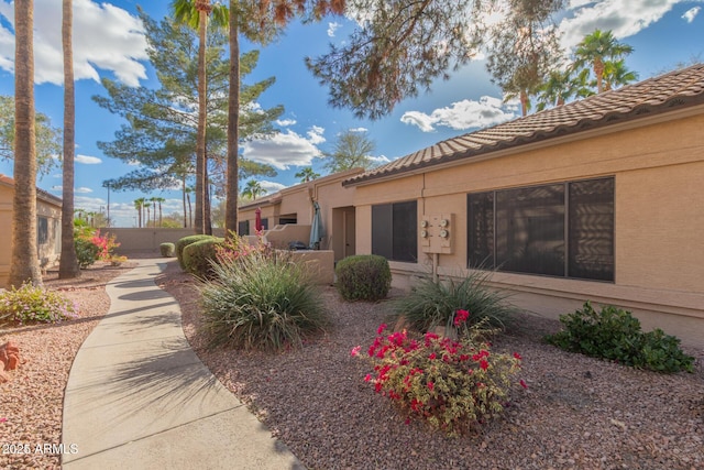 exterior space featuring a tile roof, fence, and stucco siding