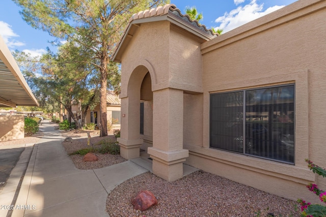 doorway to property featuring a patio area, a tile roof, and stucco siding