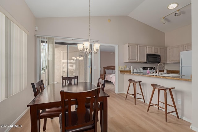 dining room featuring light wood-style floors, track lighting, a chandelier, and baseboards