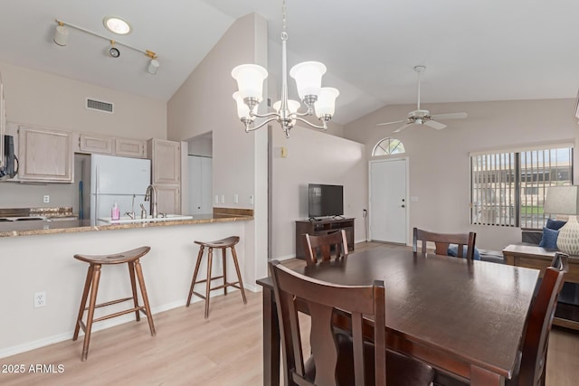 dining area featuring high vaulted ceiling, ceiling fan with notable chandelier, visible vents, light wood-style floors, and rail lighting