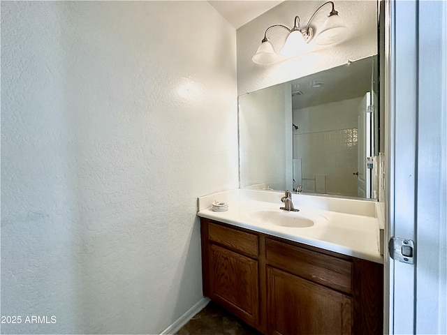 bathroom with a textured wall, baseboards, and vanity