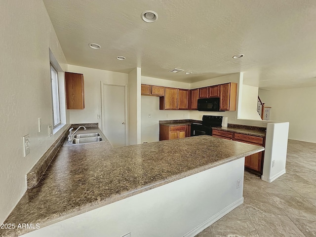 kitchen with dark countertops, visible vents, a sink, a peninsula, and black appliances