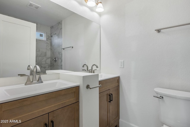 bathroom featuring tiled shower, toilet, and vanity