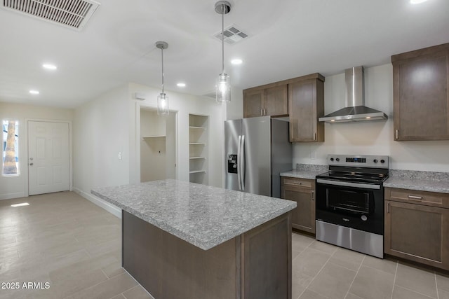 kitchen featuring wall chimney range hood, stainless steel appliances, a kitchen island, and pendant lighting