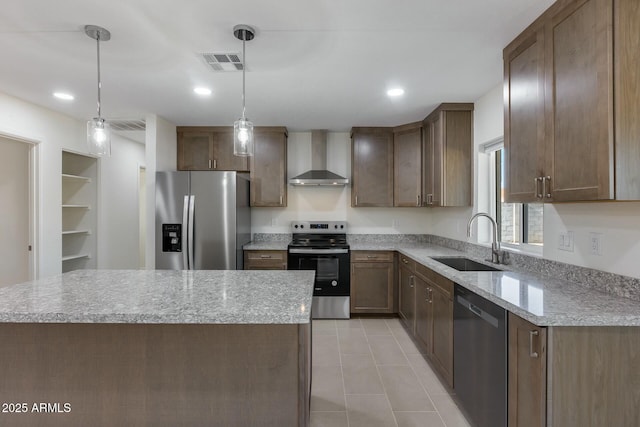 kitchen with pendant lighting, appliances with stainless steel finishes, a kitchen island, wall chimney range hood, and sink