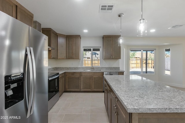 kitchen featuring pendant lighting, stainless steel appliances, a center island, and light tile patterned floors