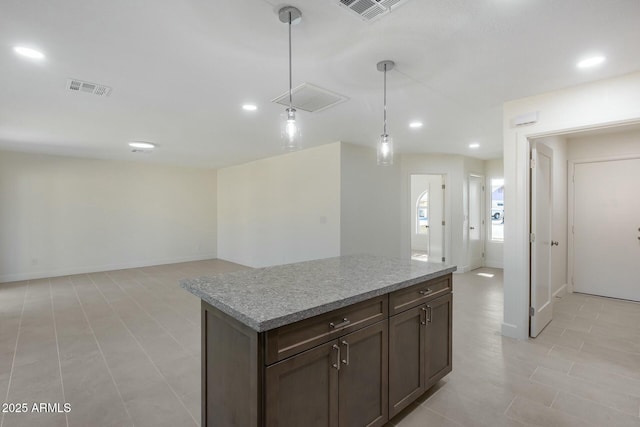 kitchen with dark brown cabinets, a center island, hanging light fixtures, and light tile patterned floors