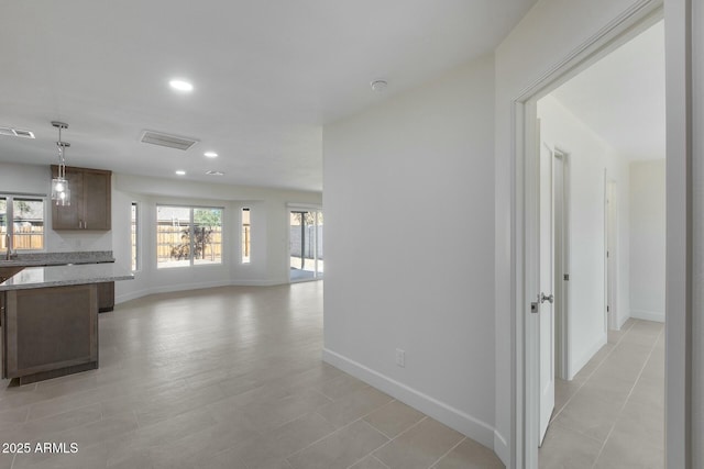 interior space featuring light tile patterned floors, plenty of natural light, light stone countertops, and hanging light fixtures